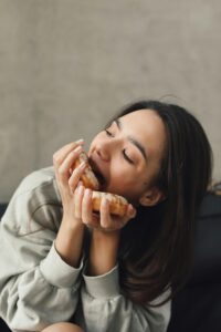 Young woman savoring a donut in a cozy indoor environment, capturing indulgence.