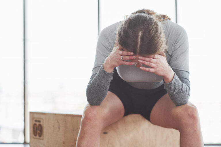 O que é vigorexia: mulher exausta após treino intenso na academia